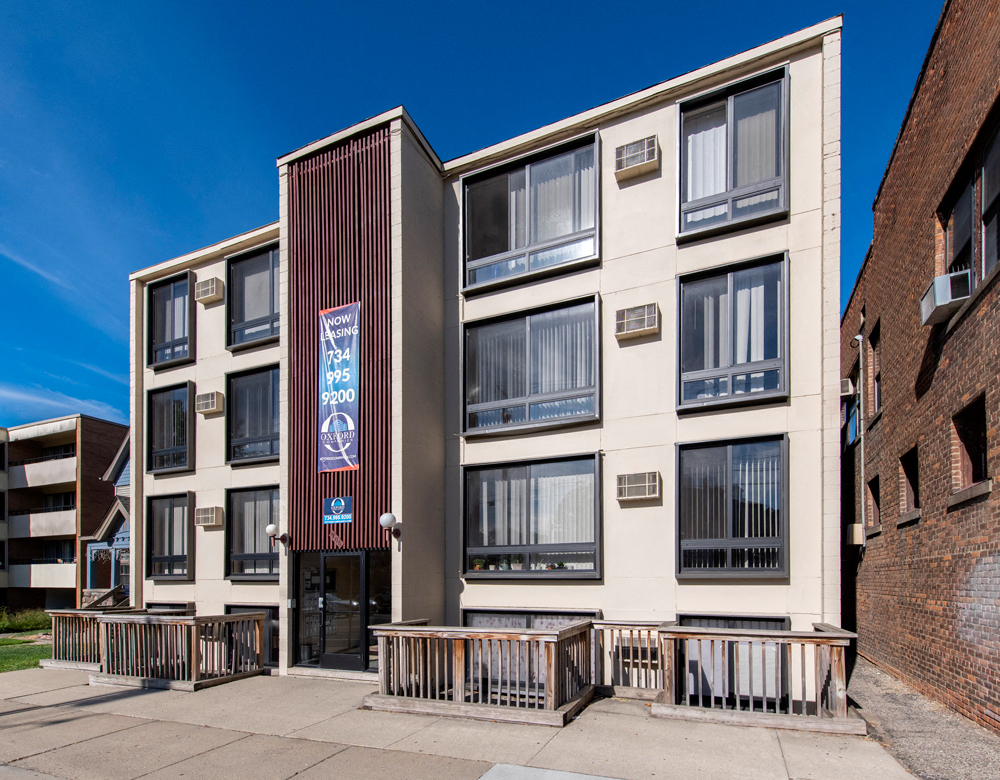 an apartment building with a sidewalk in front of it